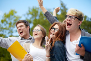 group of happy students showing triumph gesture