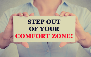 Businesswoman hands sign with step out of your comfort zone message