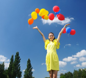 Woman releasing balloons against sky